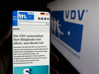 Stuttgart, Almanya - 08-07-2025: Logonun önünde Vereinigung der Vertragsfussballspieler (VDV) web sayfası bulunan kişi. Telefon ekranının merkezine odaklan.