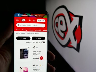 Stuttgart, Almanya - 08-18-2025: İngiliz perakende şirketi C.E.X 'in web sayfası ile cep telefonu tutan kişi. Logonun önündeki ekranda sınırlı (CeX). Telefon ekranının merkezine odaklan.