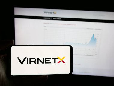 Stuttgart, Almanya - 08-18-2025: İnternet sitesinin önünde ekranda VirnetX Inc. 'in logosunun bulunduğu akıllı telefon sahibi kişi. Telefon ekranına odaklan.