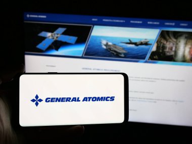 Stuttgart, Almanya - 08-18-2025: Web sitesi önünde ABD 'li savunma şirketi General Atomics' in (GA) logosunu taşıyan kişi. Telefon ekranına odaklan.