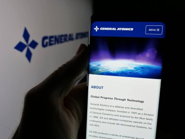 Stuttgart, Almanya - 08-18-2025: ABD 'li savunma şirketi General Atomics' in (GA) web sayfası logo önünde cep telefonu tutan kişi. Telefon ekranının merkezine odaklan.