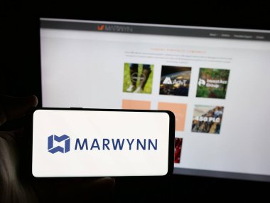 Stuttgart, Almanya - 08-18-2025: ABD tedarik zinciri şirketi Marwynn Holding Inc. 'in logosunu elinde tutan kişi web sitesinin önünde ekranda. Telefon ekranına odaklan.