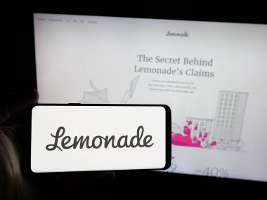 Stuttgart, Almanya - 08-18-2025: Sitenin önünde ekranda Lemonade Inc. 'in logosu olan akıllı telefon sahibi kişi. Telefon ekranına odaklan.
