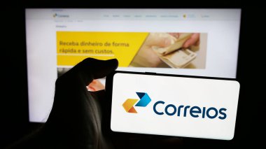 Stuttgart, Almanya - 08-19-2025: İnternet sayfasının önünde ekranda Empresa Brasileira de Correios e Telegrafos logosu bulunan kişi. Telefon ekranına odaklan.