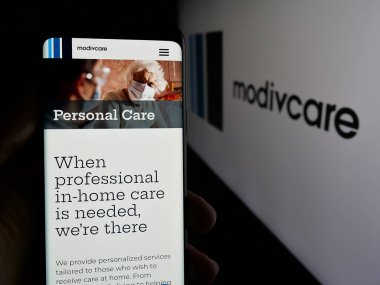 Stuttgart, Almanya - 08-20-2025: ABD 'li sağlık şirketi Modivcare Inc.' in web sayfası olan cep telefonu logonun önünde ekranda. Telefon ekranının merkezine odaklan.