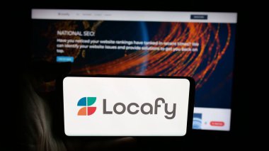 Stuttgart, Almanya - 08-20-2025: İnternet sayfasının önünde ekranda Locafy Ltd. adlı çevrimiçi pazarlama şirketinin logosuyla cep telefonu tutan kişi. Telefon ekranına odaklan.