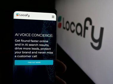 Stuttgart, Almanya - 08-20-2025: Locafy Ltd. adlı çevrimiçi pazarlama şirketinin internet sayfası ile akıllı telefon sahibi kişi logonun önünde ekranda. Telefon ekranının merkezine odaklan.
