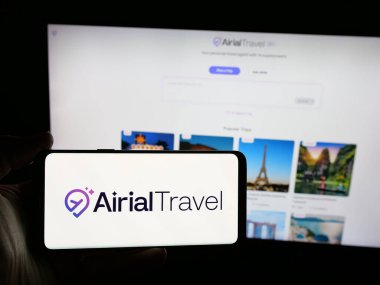 Stuttgart, Almanya - 08-21-2025: Web sitesinin önünde Airial Travel şirketinin logosuna sahip akıllı telefon sahibi kişi. Telefon ekranına odaklan.