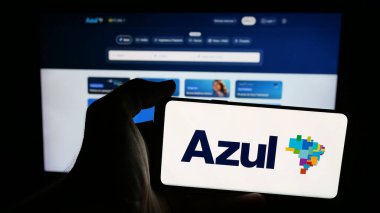 Stuttgart, Almanya - 08-21-2025: Web sayfasının önünde Azul Linhas Aereas Brasileiras havayolu logosunun bulunduğu cep telefonu sahibi kişi. Telefon ekranına odaklan.