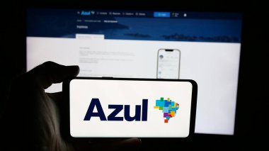 Stuttgart, Almanya - 08-21-2025: Web sayfası önünde Azul Linhas Aereas Brasileiras havayolu logosunun bulunduğu cep telefonu sahibi kişi. Telefon ekranına odaklan.