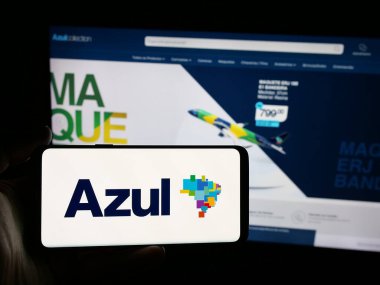 Stuttgart, Almanya - 08-21-2025: Web sitesi önünde Azul Linhas Aereas Brasileiras havayolu logosunun bulunduğu akıllı telefon sahibi kişi. Telefon ekranına odaklan.