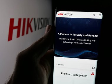 Stuttgart, Almanya - 08-22-2025: Logo önünde ekranda Hangzhou Hikvision Dijital Teknoloji web sayfası bulunan kişi. Telefon ekranının merkezine odaklan.