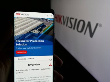 Stuttgart, Almanya - 08-22-2025: Hangzhou Hikvision Dijital Teknoloji web sayfası ile logo önünde cep telefonu tutan kişi. Telefon ekranının merkezine odaklan.