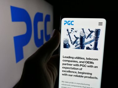 Stuttgart, Almanya - 08-22-2025: Logo önünde ekranda ABD 'li Power Grid Components Inc. (PGC) şirketinin web sayfası bulunan kişi. Telefon ekranının merkezine odaklan.