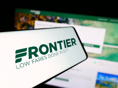 Stuttgart, Almanya - 08-22-2025: Web sitesi önünde ekranda ABD 'li havayolu şirketi Frontier Airlines Inc.' in logosuna sahip akıllı telefon. Telefon ekranının soluna odaklan.