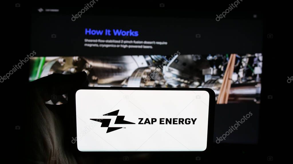 Stuttgart, Germany - 08-21-2025: Person holding cellphone with logo of US fusion power company Zap Energy Inc. on screen in front of webpage. Focus on phone display.