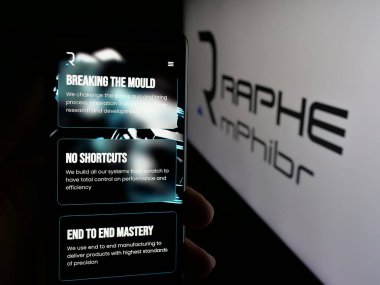 Stuttgart, Almanya - 08-22-2025: Hintli İHA şirketi Raphe mPhibr Pvt. web sayfası ile cep telefonu tutan kişi Ltd. Logonun önünde ekranda. Telefon ekranının merkezine odaklan.