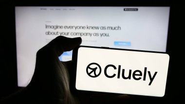 Stuttgart, Almanya - 08-22-2025: Web sayfasının önündeki ekranda US AI yardımcı şirketi Cluely Inc. 'in logosunun bulunduğu cep telefonu sahibi kişi. Telefon ekranına odaklan.