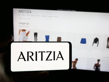 Stuttgart, Almanya - 08-22-2025: Kanadalı giyim perakende şirketi Aritzia LP 'nin logosuna sahip akıllı telefon sahibi kişi web sitesinin önünde ekranda. Telefon ekranına odaklan.