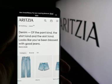 Stuttgart, Almanya - 08-22-2025: Kanadalı giyim perakende şirketi Aritzia LP 'nin web sayfası ile akıllı telefon sahibi kişi logonun önünde ekranda. Telefon ekranının merkezine odaklan.