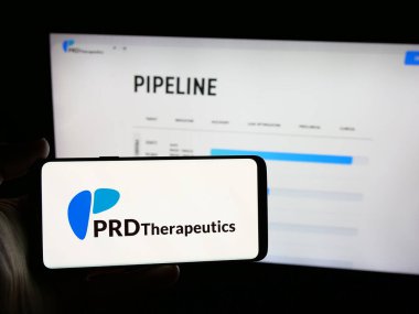 Stuttgart, Almanya - 08-22-2025: Sitenin önünde ekranda biyoteknoloji şirketi PRD Therapeutics Inc. 'in logosuna sahip akıllı telefonu tutan kişi. Telefon ekranına odaklan.