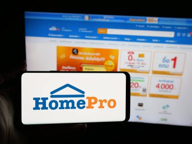 Stuttgart, Almanya - 08-25-2025: İnternet sitesi önünde üzerinde Tayland ev geliştirme perakende şirketi HomePro 'nun logosu bulunan akıllı telefon sahibi kişi. Telefon ekranına odaklan.