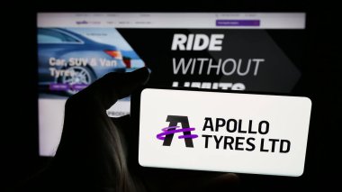 Stuttgart, Almanya - 08-25-2025: Hint lastik şirketi Apollo Lastik Limited 'in logosuna sahip cep telefonu sahibi kişi web sayfasının önünde ekranda. Telefon ekranına odaklan.