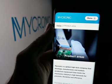 Stuttgart, Almanya - 08-25-2025: İsveçli elektronik şirketi Mycronic AB 'nin web sayfası olan akıllı telefon sahibi kişi logonun önünde ekranda. Telefon ekranının merkezine odaklan.