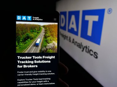 Stuttgart, Almanya - 09-25-2025: Logo önündeki ekranda Yük Analiz Şirketi DAT Çözümleri LLC 'nin web sayfası ile akıllı telefon tutan kişi. Telefon ekranının merkezine odaklan.