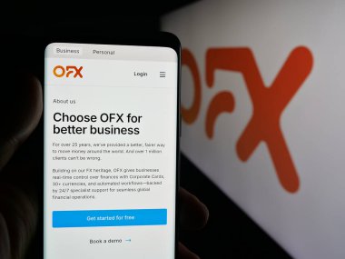Stuttgart, Almanya - 09-25-2025: Avustralyalı fintech şirketi OFX Limited 'in web sayfası olan akıllı telefon sahibi kişi logonun önünde ekranda. Telefon ekranının merkezine odaklan.