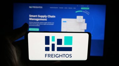 Stuttgart, Almanya - 09-25-2025: Cep telefonunda nakliye şirketi Freightos Lt. logosu olan kişi web sayfasının önünde ekranda. Telefon ekranına odaklan.