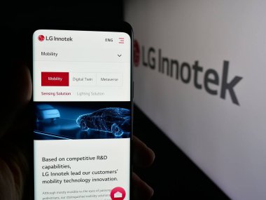 Stuttgart, Almanya - 09-25-2025: Koreli elektronik şirketi LG Innotek Co. Ltd 'nin internet sayfası ile cep telefonu tutan kişi logonun önünde ekranda. Telefon ekranının merkezine odaklan.