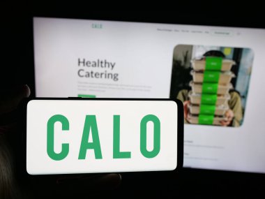 Stuttgart, Almanya - 09-25-2025: Suudi Arabistan yemek şirketi Calo Inc. 'in logosunu elinde tutan kişi web sitesinin önünde ekranda. Telefon ekranına odaklan.
