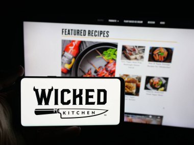 Stuttgart, Almanya - 09-25-2025: ABD 'li vejetaryen mutfak şirketi Wicked Foods Inc.' in logosunu elinde tutan kişi web sitesinin önünde ekranda. Telefon ekranına odaklan.