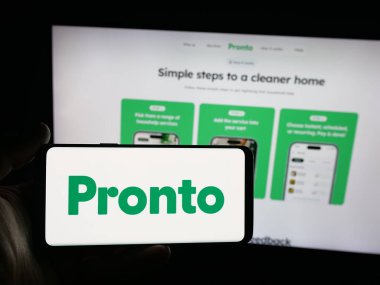 Stuttgart, Almanya - 09-26-2025: Hintli ev yardım uygulaması şirketi Pronto 'nun logosunun bulunduğu akıllı telefonu web sitesinin önünde tutan kişi. Telefon ekranına odaklan.