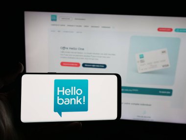 Stuttgart, Almanya - 09-26-2025: İnternet sitesinin önünde üzerinde Fransız fintech şirketi Hello Bank 'ın logosu olan akıllı telefon tutan kişi. Telefon ekranına odaklan.