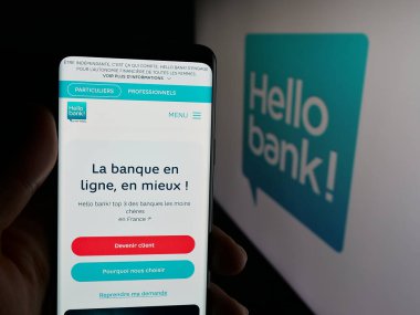Stuttgart, Almanya - 09-26-2025: Fransız fintech şirketi Hello Bank 'ın internet sayfası ile logo önünde cep telefonu tutan kişi. Telefon ekranının merkezine odaklan.