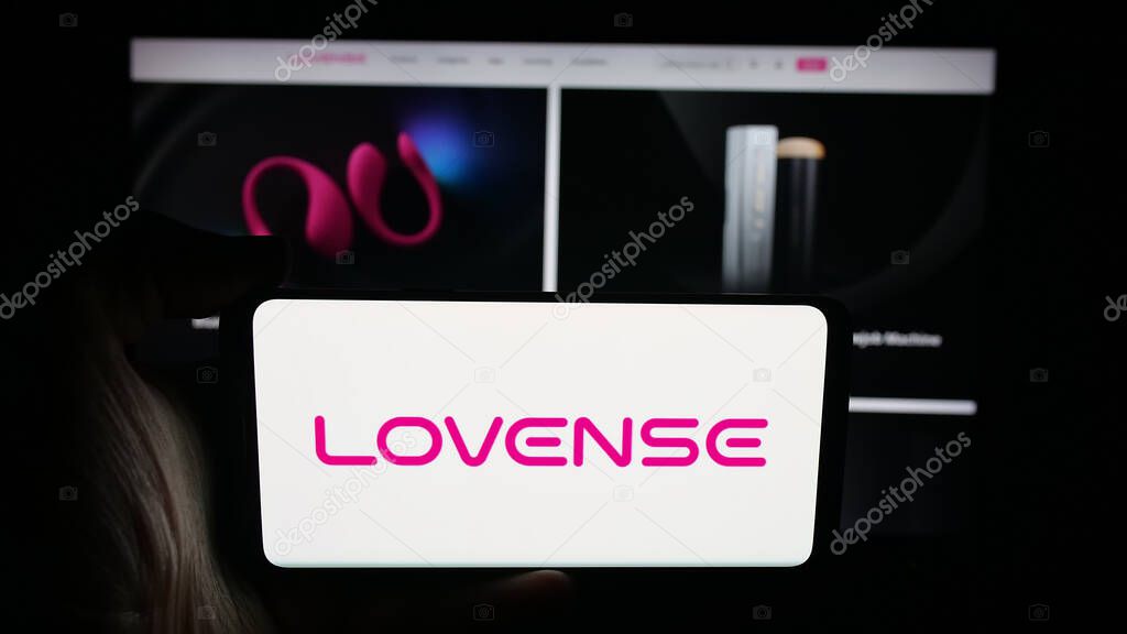 Stuttgart, Germany - 09-25-2025: Person holding cellphone with logo of sex toy company Lovense (Hytto Pte. Ltd.) on screen in front of webpage. Focus on phone display.