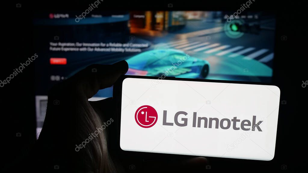 Stuttgart, Germany - 09-25-2025: Person holding mobile phone with logo of Korean electronics company LG Innotek Co. Ltd on screen in front of web page. Focus on phone display.