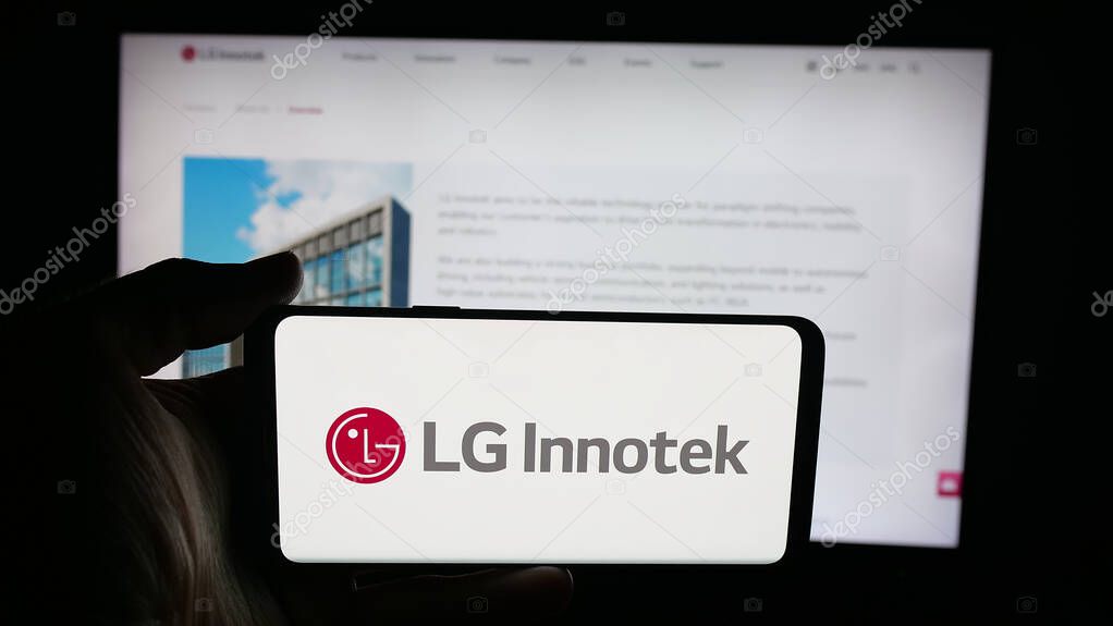 Stuttgart, Germany - 09-25-2025: Person holding cellphone with logo of Korean electronics company LG Innotek Co. Ltd on screen in front of webpage. Focus on phone display.