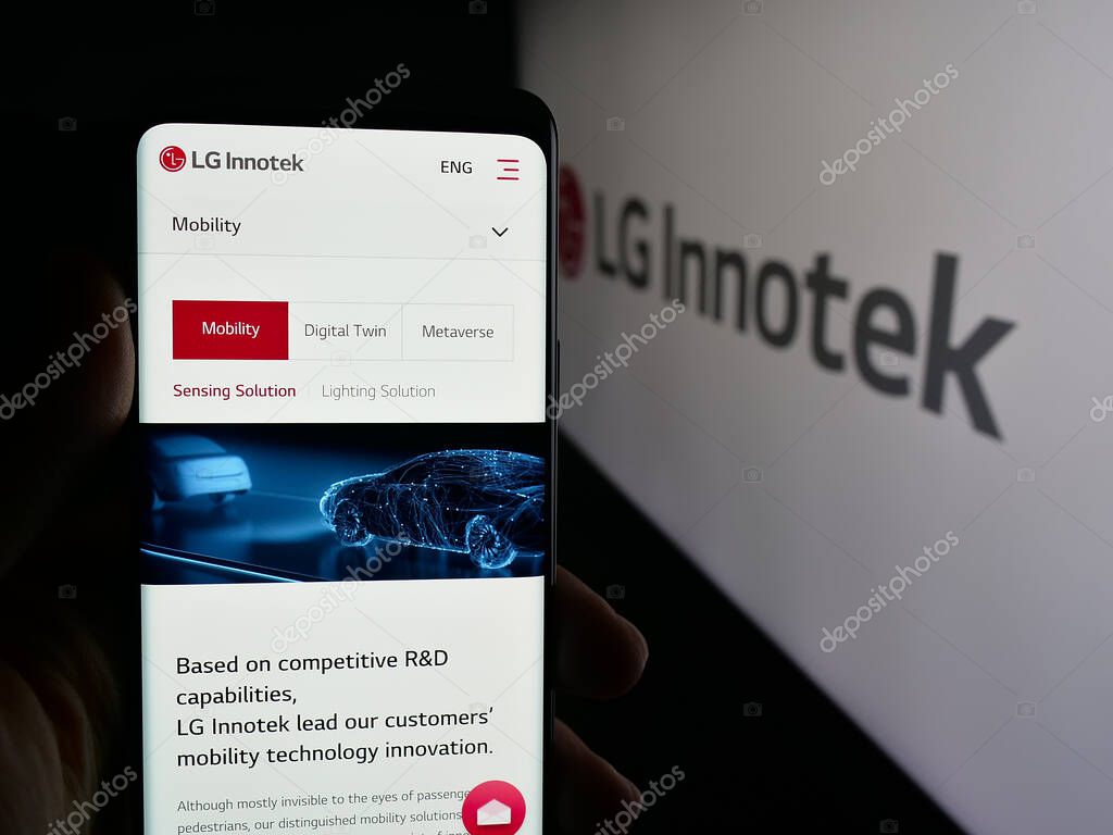 Stuttgart, Germany - 09-25-2025: Person holding cellphone with webpage of Korean electronics company LG Innotek Co. Ltd on screen in front of logo. Focus on center of phone display.