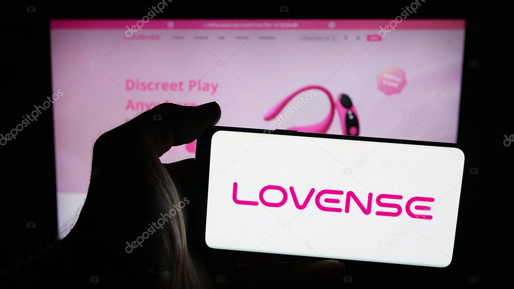 Stuttgart, Germany - 09-25-2025: Person holding mobile phone with logo of sex toy company Lovense (Hytto Pte. Ltd.) on screen in front of web page. Focus on phone display.