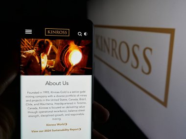 Stuttgart, Almanya - 09-27-2025: Maden şirketi Kinross Gold Corporation 'ın web sayfası ile logo önünde cep telefonu tutan kişi. Telefon ekranının merkezine odaklan.
