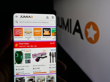 Stuttgart, Almanya - 09-29-2025: E-ticaret şirketi Jumia Technologies 'in web sayfası ile akıllı telefonu olan kişi logonun önünde ekranda. Telefon ekranının merkezine odaklan.