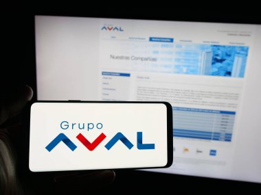 Stuttgart, Almanya - 09-29-2025: Web sitesi önünde ekranda Grupo Aval Acciones y Valores S.A. şirketinin logosunu taşıyan kişi. Telefon ekranına odaklan.