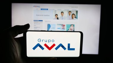 Stuttgart, Almanya - 09-29-2025: Web sayfası önünde ekranda Grupo Aval Acciones y Valores S.A. şirketinin logosuyla cep telefonu tutan kişi. Telefon ekranına odaklan.