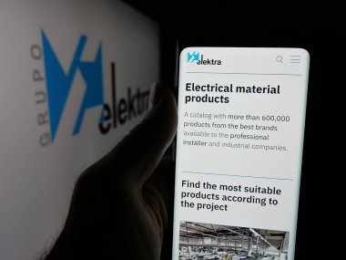 Stuttgart, Almanya - 09-29-2025: Meksikalı perakende şirketi Grupo Elektra 'nın web sayfası olan akıllı telefon sahibi kişi logonun önünde ekranda. Telefon ekranının merkezine odaklan.
