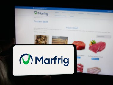 Stuttgart, Almanya - 09-29-2025: Gıda şirketi Marfrig Global Foods 'un logosuna sahip akıllı telefon sahibi kişi web sitesinin önünde ekranda. Telefon ekranına odaklan.