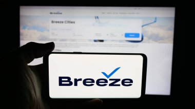 Stuttgart, Almanya - 09-29-2025: Web sayfasının önünde ekranda ABD 'li düşük maliyetli havacılık şirketi Breeze Airways' in logosuyla cep telefonu tutan kişi. Telefon ekranına odaklan.