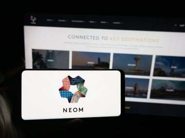 Stuttgart, Almanya - 09-29-2025: Suudi Arabistan emlak projesi NEOM 'un logosunun bulunduğu akıllı telefonu web sitesinin önünde elinde tutan kişi. Telefon ekranına odaklan.